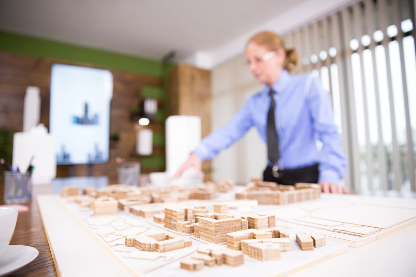una chica en una oficina delante de una maqueta, simulando un estudio de viabilidad inmobiliaria